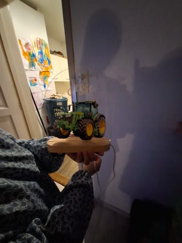 Recensent houdt het verlichte tractor nachtlampje vast in een kamer.
