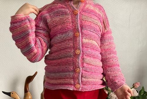 Customer's finished multi-colored pink cardigan from the knitting box, shown on a child.