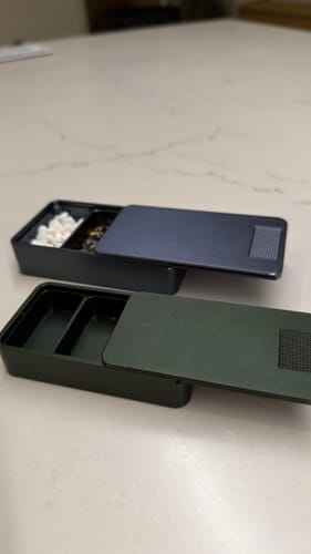 Customer's two open Mission Cases, one blue and one green, on a countertop. The blue case is filled with pills.