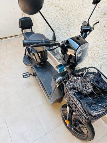 Cliente muestra su bicicleta eléctrica negra Kiwo GY801 ensamblada, estacionada en un patio.