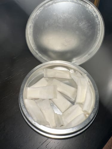 Customer's open silver tin showing multiple Refreshing Chill Nicotine Pouches inside.