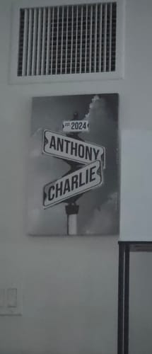 Customer's personalized street sign canvas hung on a wall, showing the names 'Anthony' and 'Charlie' and the year '2024'.