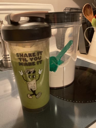 Avis d'un client montrant son shake de protéine IsoGen® vert dans un shaker à côté d'un contenant de poudre.