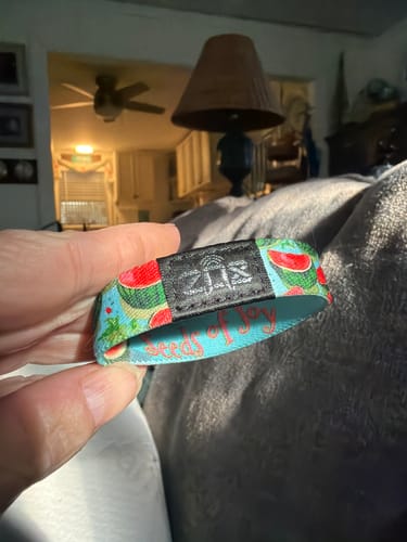 Close-up of a customer's hand holding the colorful Seeds Of Joy Bracelet with a watermelon pattern.