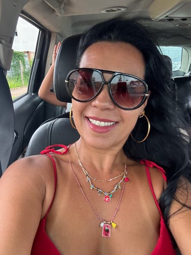 Cliente sorrindo e usando os estilosos Óculos Veneza dentro de um carro.