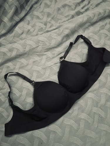 Customer's black Lovemère Seamless Nursing Bra laid out on a patterned bed.