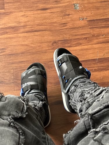Customer wearing a pair of black OG Mystery DracoSlides with blue buckles and distressed jeans.