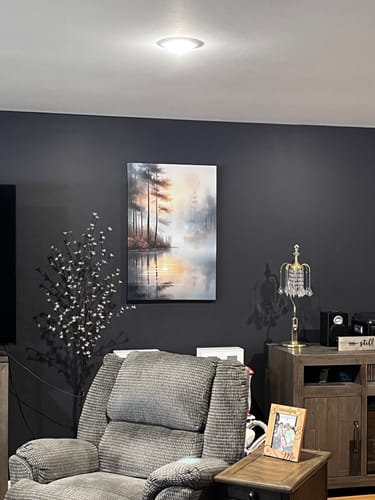 Customer's Misty Lake Wall Art hanging on a dark gray wall in a cozy living room.