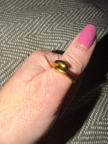Reviewer's hand wearing a gold-colored, overlapping ring from the clearance sale on their thumb.