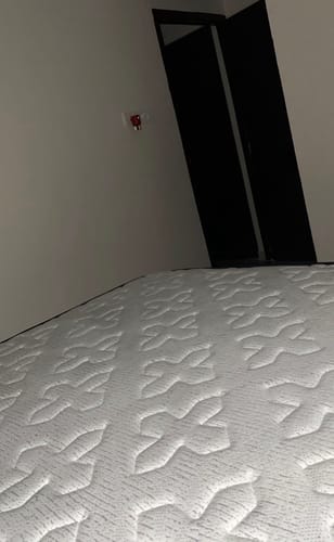 Customer's close-up of the Flo Float™ Mattress, showing its white, textured surface in a bedroom.