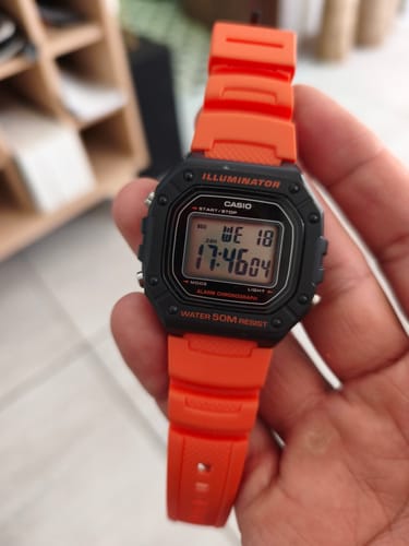 Un cliente sostiene en la mano el Reloj Casio Vintage con una llamativa correa naranja.