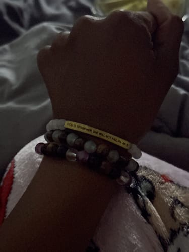 Close-up of a reviewer's wrist wearing the yellow motivational bracelet stacked with other beaded bracelets.