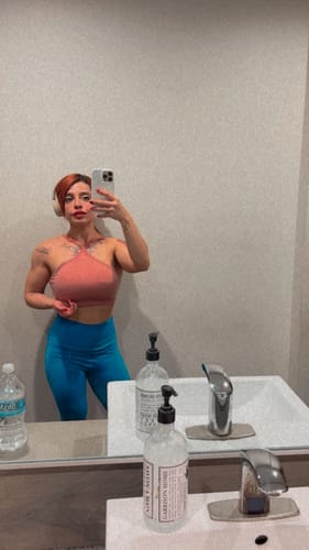 Clienta mostrando su físico musculoso en un espejo, resultado del uso de OXA-K10 KASSEL PHARMA.