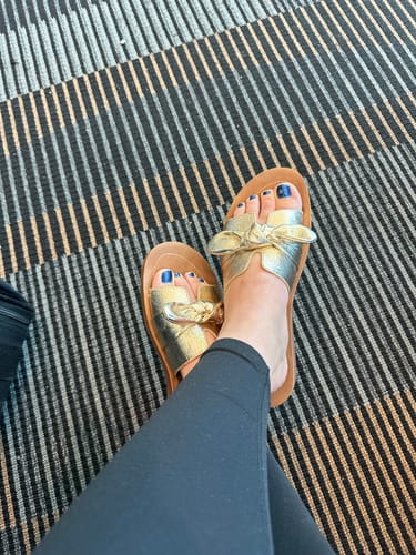 Customer wearing the Too Cute Gold Crinkle Sandals with black leggings.