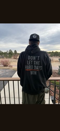 Reviewer from behind wearing the black Hard Days - Hoodie, showing the 'DON'T LET THE HARD DAYS WIN' text on the back.