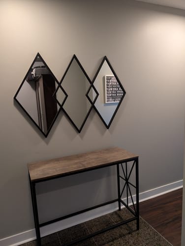 Customer's black Black Diamond Metal Mirror mounted on a gray wall above a modern console table.