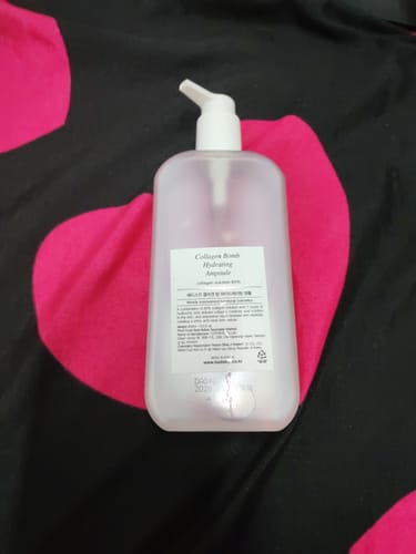 Reviewer shows the back of the translucent bottle of Bad Skin Collagen Bomb Hydrating Ampoule.