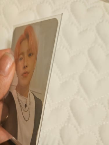 Customer holding a photocard in a thick Premium Photocard Sleeve, showing the edge up close.