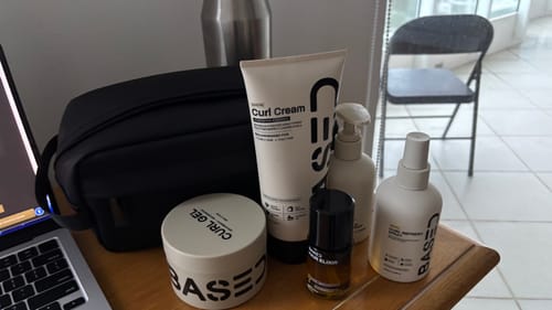 Reviewer's Curl Cream tube displayed on a desk with other hair products from the Based collection.