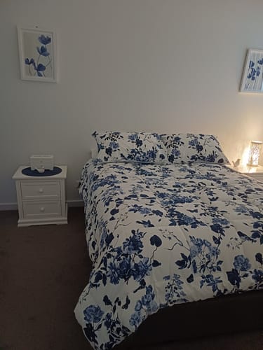 Customer's two Hamptons Botanica I Art Prints with blue florals, hanging in a bedroom and matching the bedding.