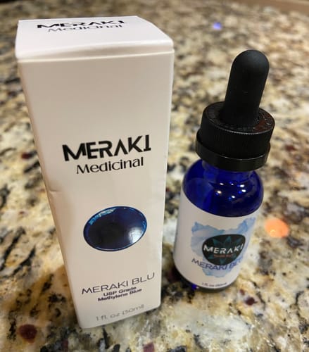 Customer shows the blue Meraki Blu bottle with its dropper next to the white packaging.