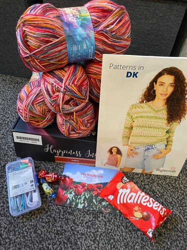 Customer's March 26 - Ladies Box Every Month showing colorful yarn, a pattern book, accessories, and treats.