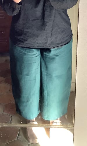 Une cliente porte le pantalon Briac, montrant sa coupe ample en lin vert.