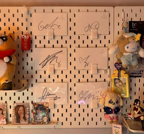 Reviewer's signed postcards in clear resealable sleeves displayed on a white pegboard with other decorations.