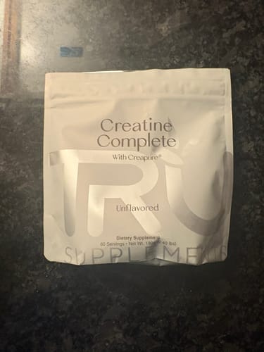Customer's white pouch of unflavored Creatine Complete supplement on a dark countertop.