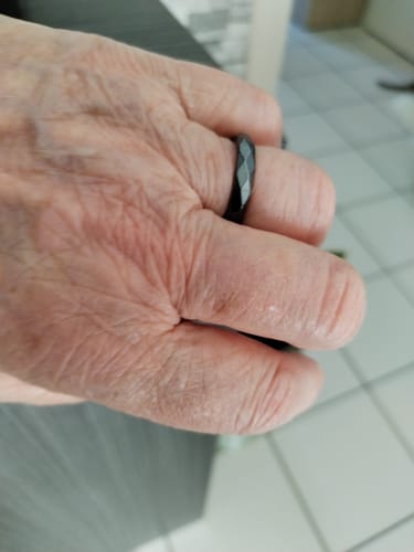 Client montrant sa bague en hématite noire et facettée à son doigt.