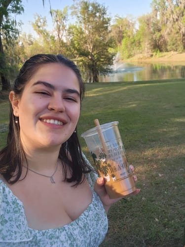 Customer smiling outdoors wearing a silver-toned initial necklace and small earrings from the Valentines Bundle.