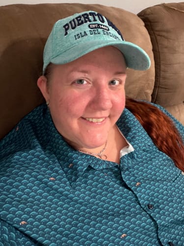 Reviewer smiling while wearing the teal Wee Cows KUNUFLEX Short Sleeve Shirt, showing off the manatee pattern.