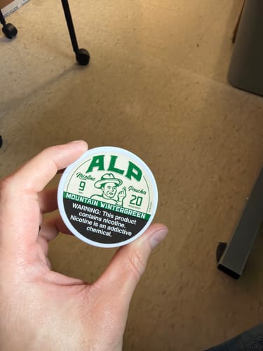 Customer's hand holding a round tin of Mountain Wintergreen Nicotine Pouches.