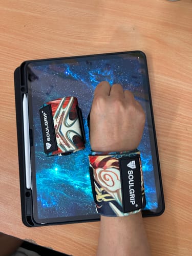 Reviewer's hand wearing the colorful Thunderstrike Wrist Wrap, with a matching one rolled up next to it.