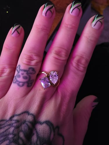 Customer wearing the Navae Birthstone Ring with its sparkling pear-cut and purple radiant-cut stones.
