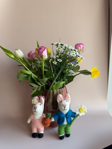 Customer using the beige Dune backdrop for a product photo of two felt bunnies and a vase of flowers.