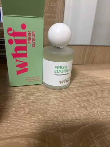 Customer's frosted bottle of Fresh Elysium perfume next to its green packaging box on a wooden surface.
