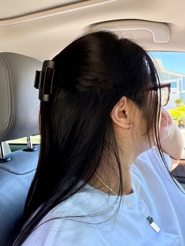 Reviewer's black cloud clip holding back their long, dark hair in a half-up style.