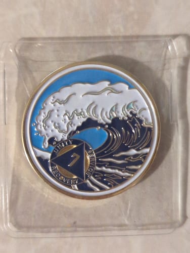 Customer's 7 Year Sobriety Medallion with a crashing wave design, shown in its clear plastic packaging.