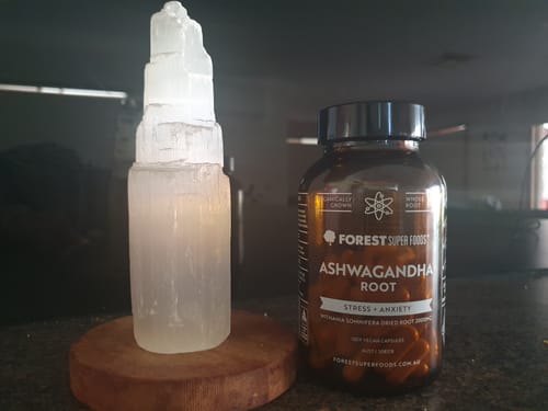 Reviewer's bottle of Organic Ashwagandha Capsules on a dark counter next to a decorative crystal.