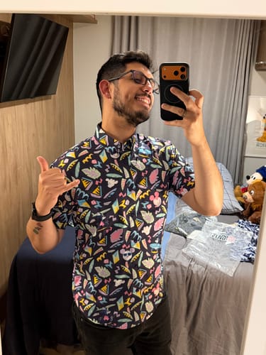 Reviewer smiling in a mirror selfie wearing the colorful Disney "Surfin' Mickey" shirt and making a shaka sign.