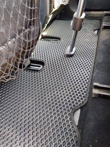 Recenzent pokazuje dopasowany, szary dywanik samochodowy na tylnej podłodze w Citroenie C4 Grand Picasso II.