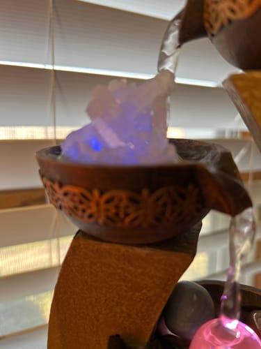 Customer's crystal from the VIP Crystal Club glowing with blue light inside a decorative water fountain.