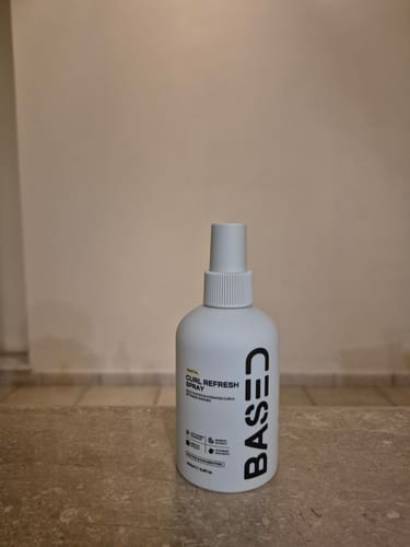 Reviewer's white bottle of Based Curl Refresh Spray sitting on a counter.