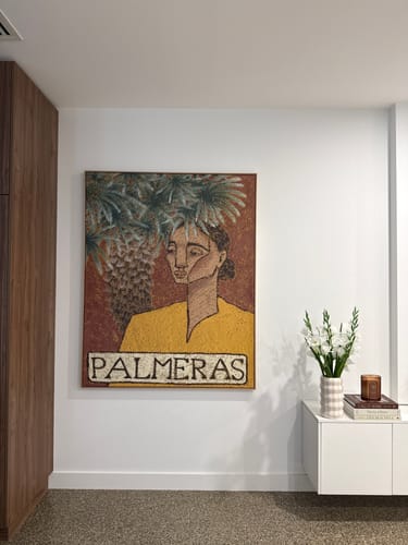 Customer's 'Palmeras' canvas art print hanging on a white wall in a modern lounge room next to a white console.
