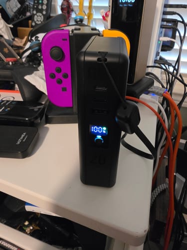 Customer's black MagBank Universal stands on a desk. The digital display shows it is 100% charged.