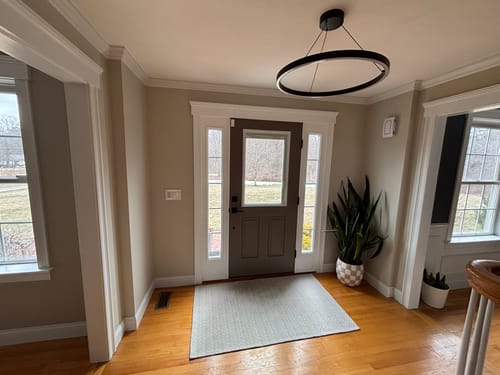Reviewer's updated entryway showing the Raise & Lower Blinds Glass and Frame Kit installed on a dark brown door.