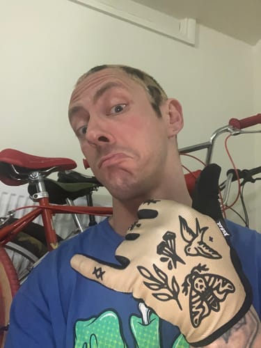 Reviewer holds up a tan Gravity Glove, showing the detailed tattoo-style graphics on the back.