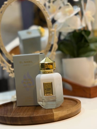 Customer's MUSC BLANC perfume bottle with its elegant gold cap, displayed next to its box on a wooden tray.