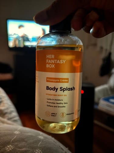 Customer holding a clear bottle of the golden-yellow Pineapple Crème Body Splash.
